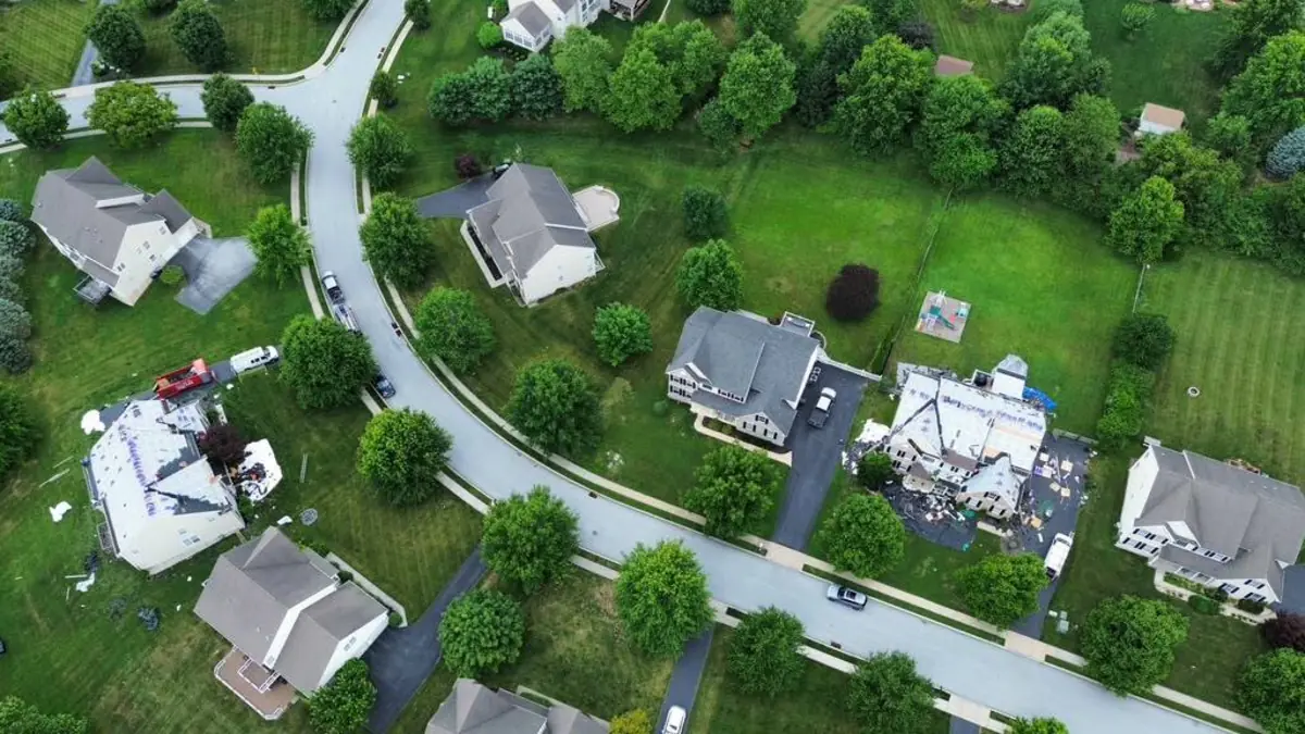 High aerial view of a neighborhood with roof replacements underway on two separate homes at the same time